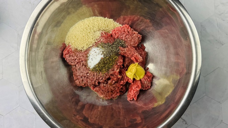 ground beef with assorted seasonings in metal bowl