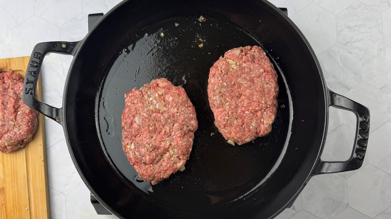 two beef patties in cast iron skillet