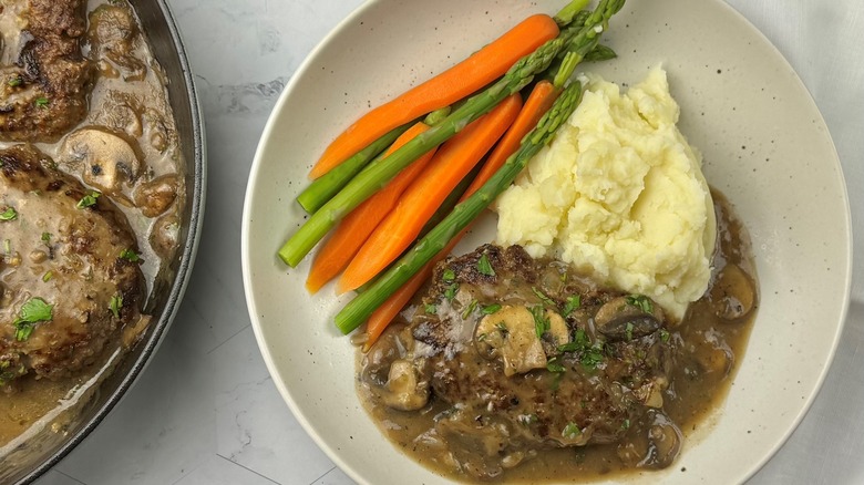 salisbury steak portion with gravy, mashed potatoes, carrots, and asparagus