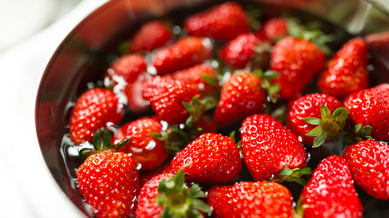 strawberries soaking in a bowl of water