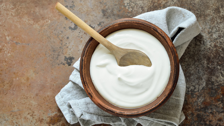 Wooden bowl of plain yogurt with wooden spoon