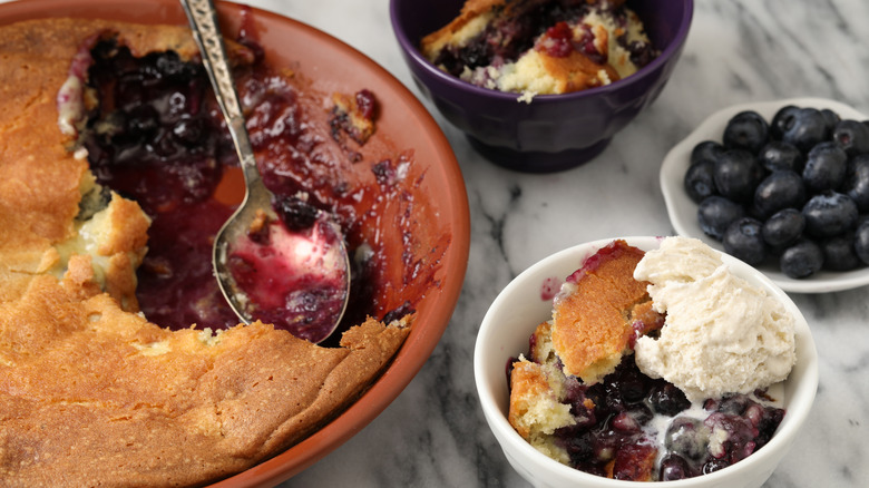 Blueberry buckle pie in baking dish with serving topped with ice cream