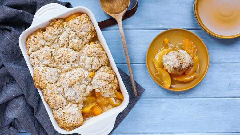 Peach cobbler with biscuit topping in white casserole dish