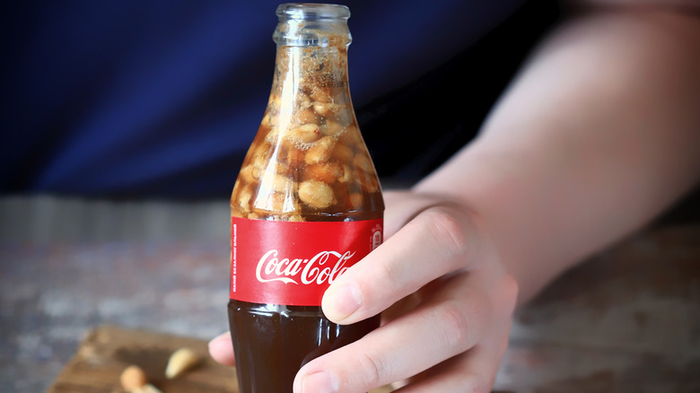 hand holding Coca-Cola with peanuts