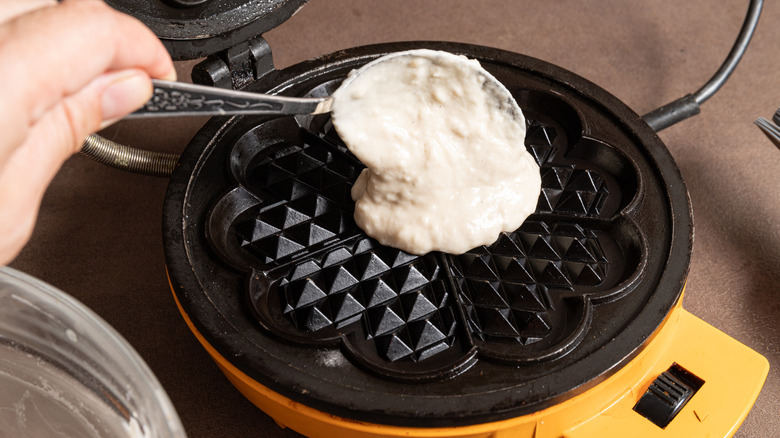 adding waffle batter to iron