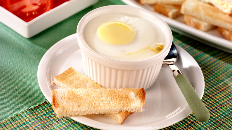 Ramekin filled with coddled egg next to toast soldiers