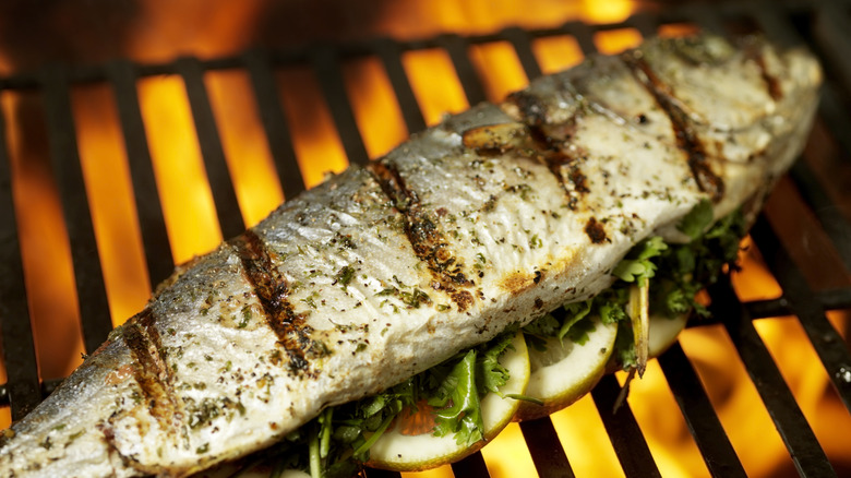 whole fish on the grill stuffed with fresh herbs and lemon slices