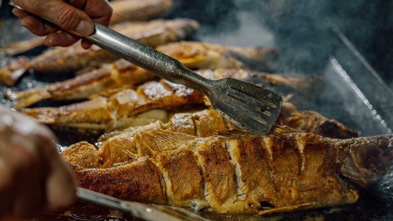 man cooking fish on grill