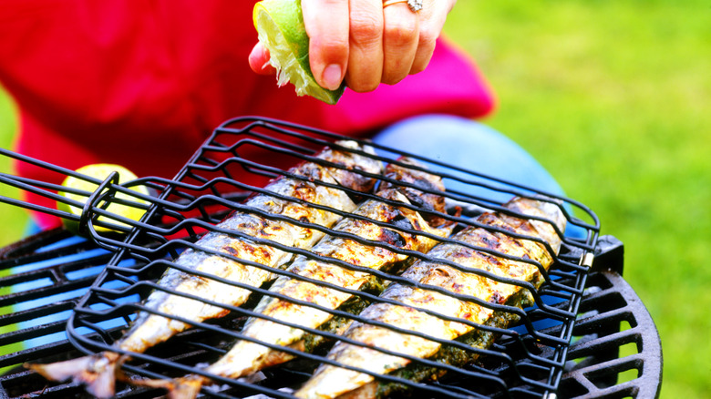 person seasoning grilled fish while cooking