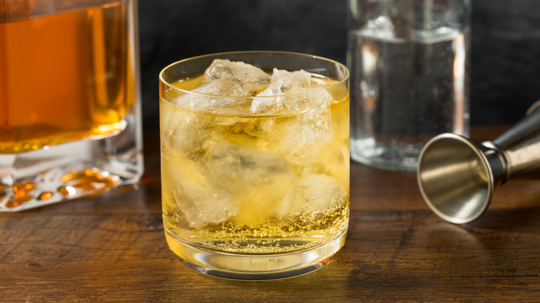 Whiskey highball in a rocks glass with bottle and jigger