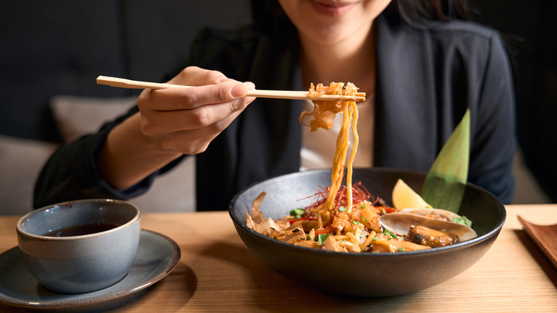 Woman eating Japanese noodles with chopsticks