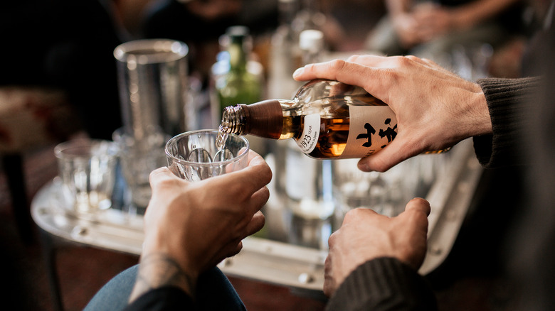 Hand pouring Japanese whisky into a glass for tasting