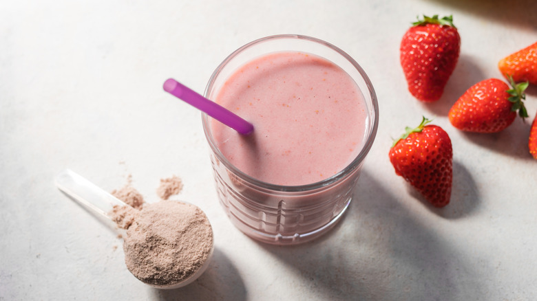 A strawberry fruit smoothie in a glass next to strawberries