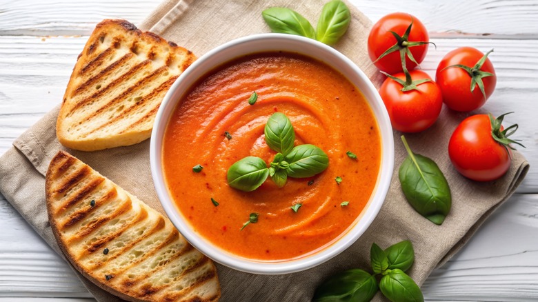 a bowl of creamy tomato soup with bread