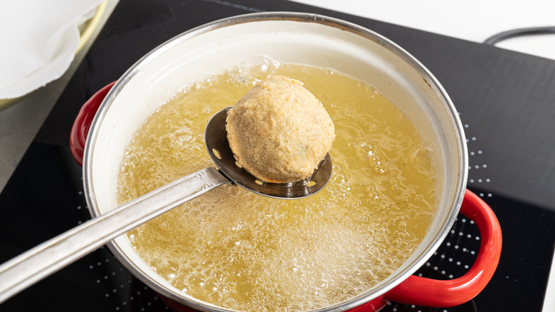 slotted spoon holding croquette over oil