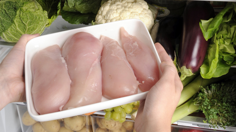 Person removing chicken breasts from fridge