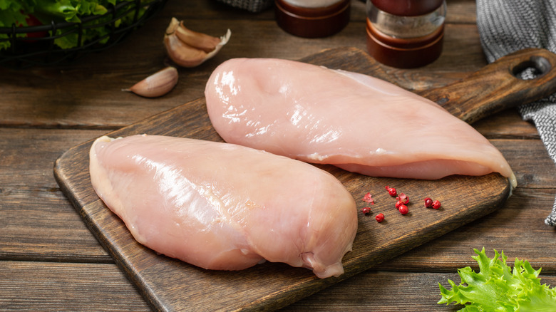 Chicken breasts on wooden chopping board