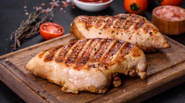 Cooked chicken breasts on chopping board