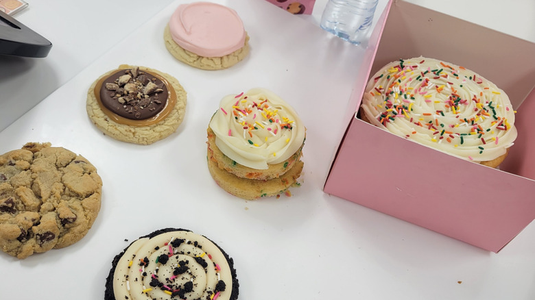 A variety of Crumbl desserts sit on a white table