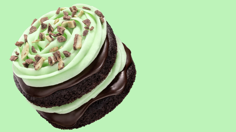 The new mint chocolate cake from Crumbl on a mint green background