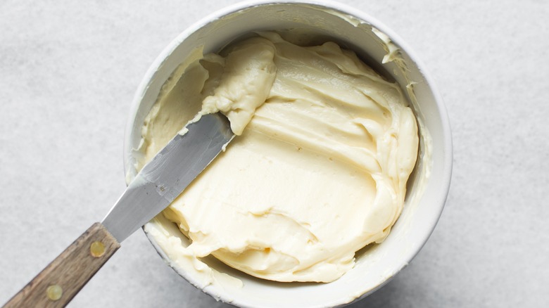 bowl of vanilla frosting with spreading knife