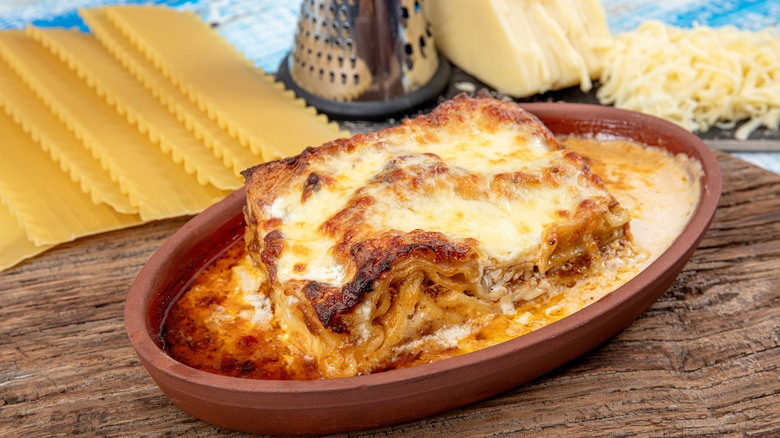 baked lasagna in dish next to uncooked ingredients