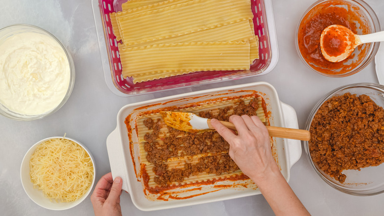 person preparing lasagna with spatula