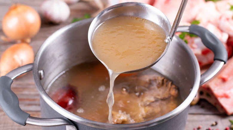 chicken stock ladled into a pot