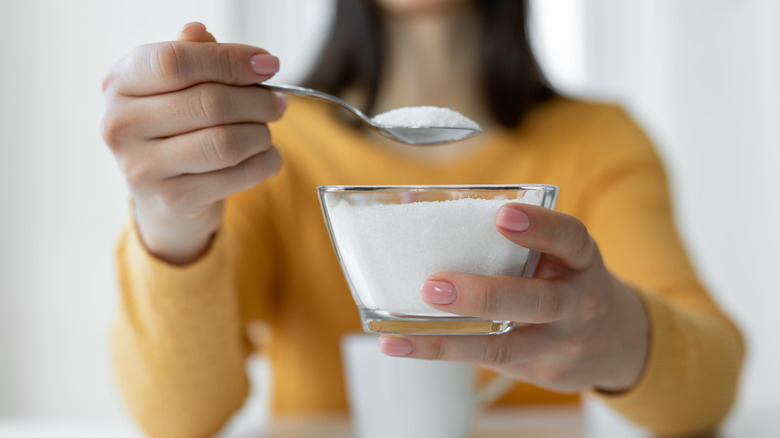 Woman scooping sugar from bowl