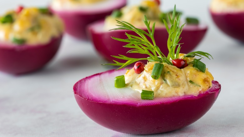 Beet-dyed deviled egg with herbs and pink pepper