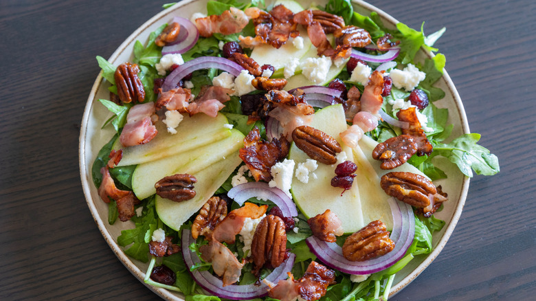 A fall salad featuring crispy pancetta, sliced apples, and candied pecans