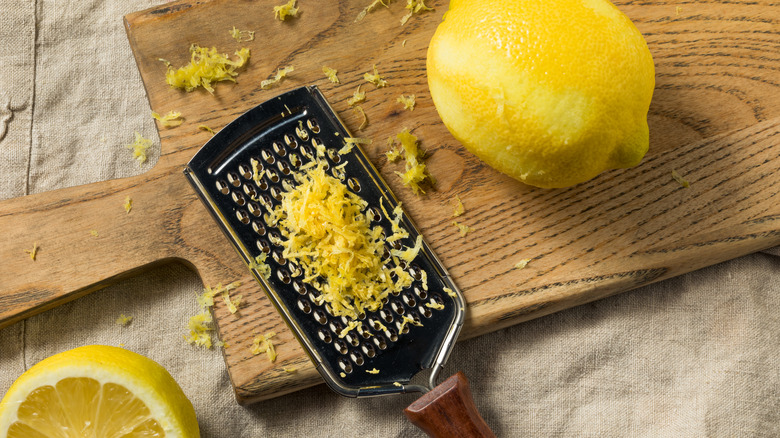 Lemon and zester on a wooden cutting board