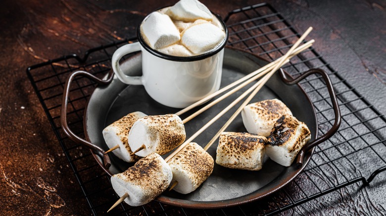 Toasted marshmallows next to a cup of marshmallows