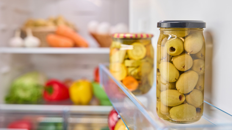 green olives in a jar in a refrigerator