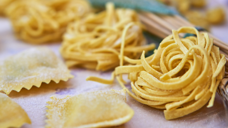 Different fresh pasta shapes drying on a table