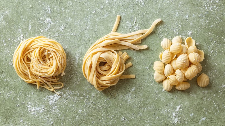 Fresh spaghetti, tagliatelle, and shells pasta on a floured work surface