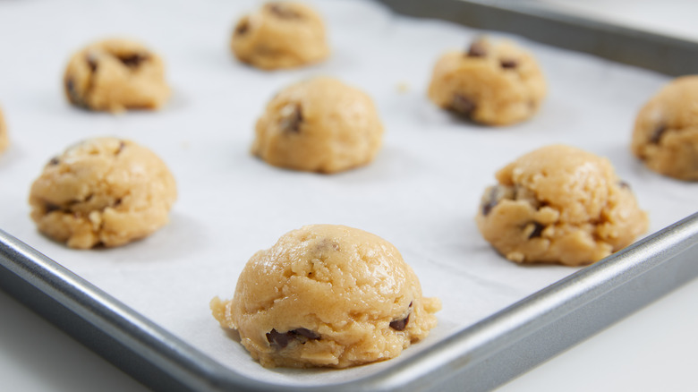 Unbaked chocolate chip cookies on a baking sheet