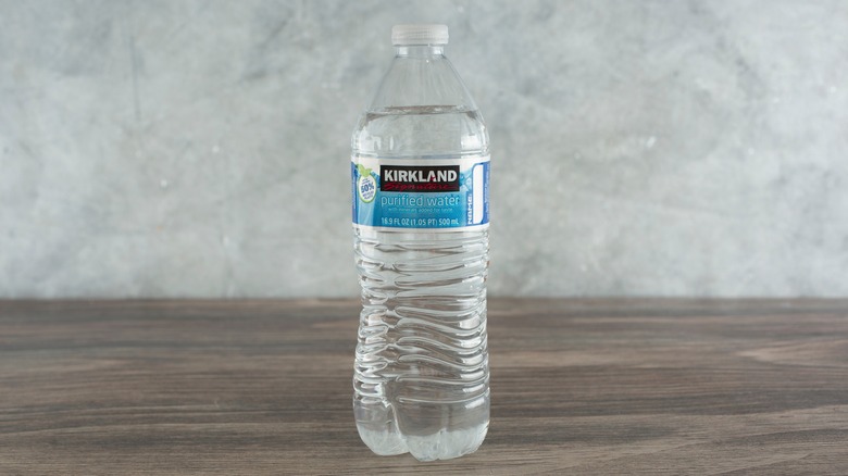 A full Kirkland Signature branded water bottle on a wood table