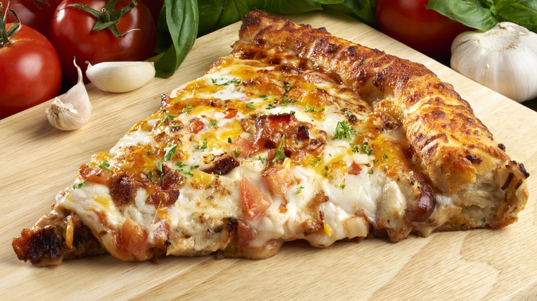 Slice of cooked pizza with chicken and bacon topping