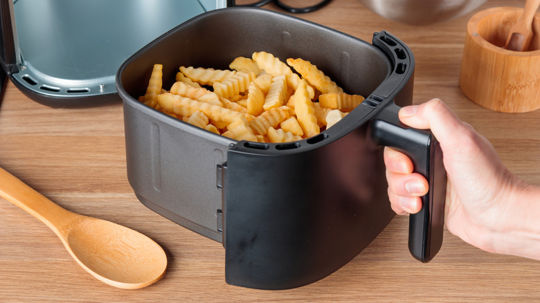 A basket of french fries being pulled out of the air fryer