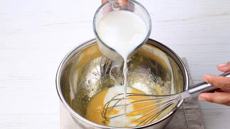 Person pouring milk into a batter