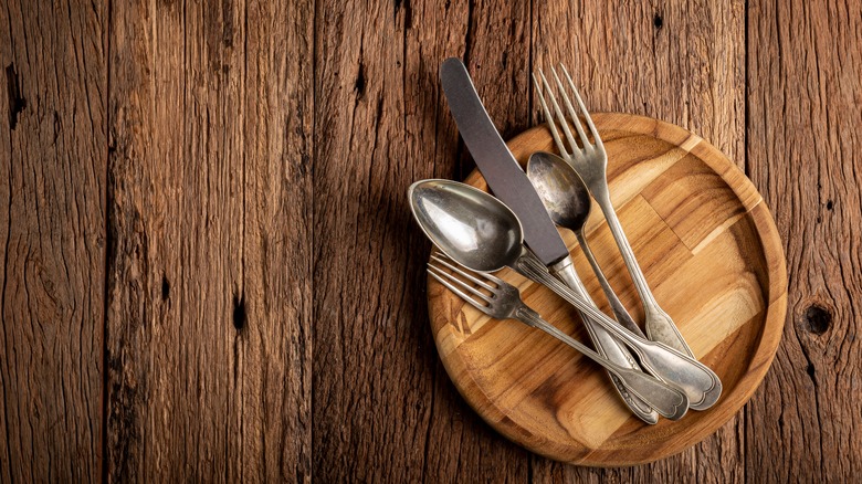 Silver cutlery on a wooden board