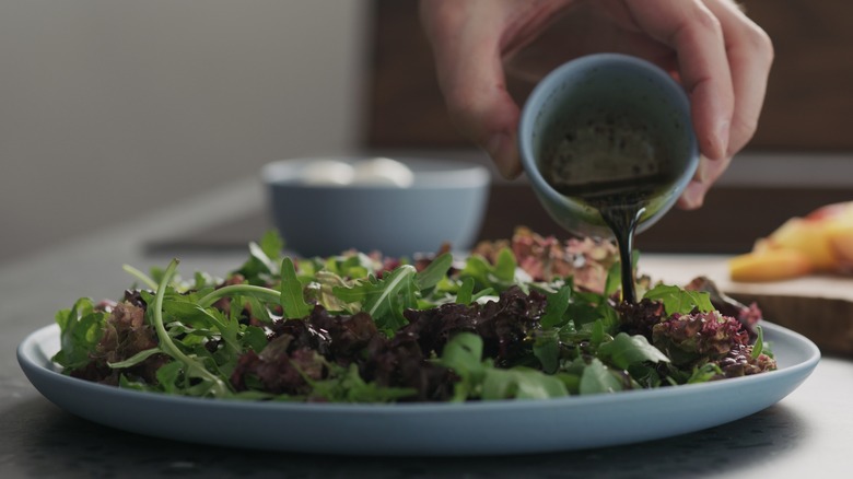 Pouring salad dressing over green leaves