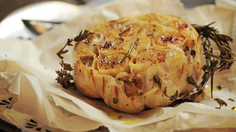 Roasted garlic on a parchment paper with herbs