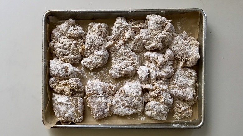 raw flour coated chicken pieces in pan
