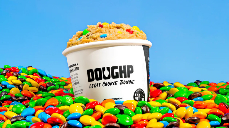 Doughp raw cookie dough container in pile of M&M's