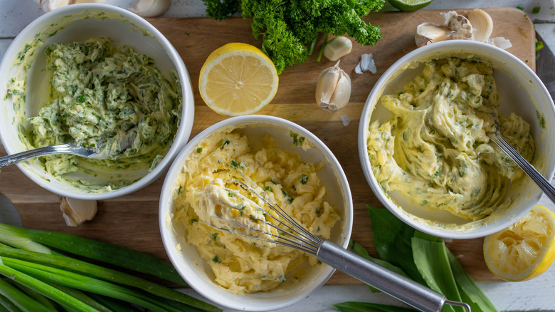 Three bowls of herb butters with ingredients