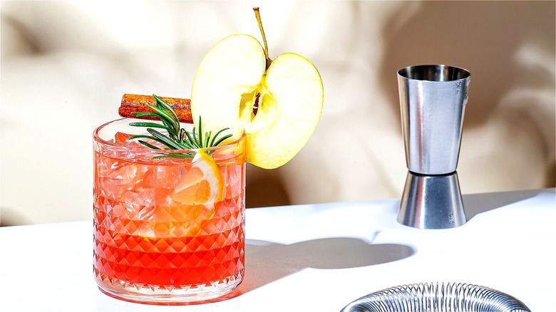 Red apple cocktail in a clear glass with fresh rosemary