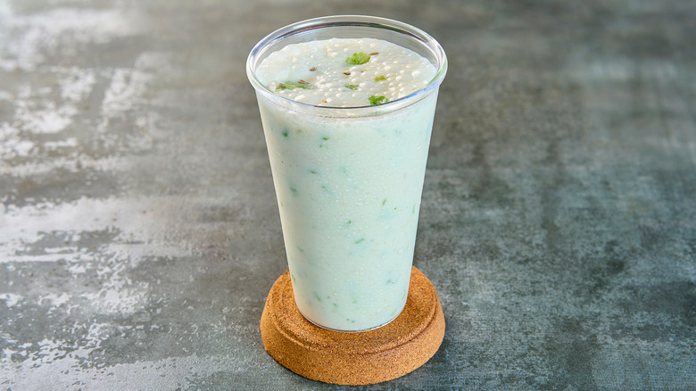 A glass of buttermilk with herbs mixed in sits on an elevated coaster