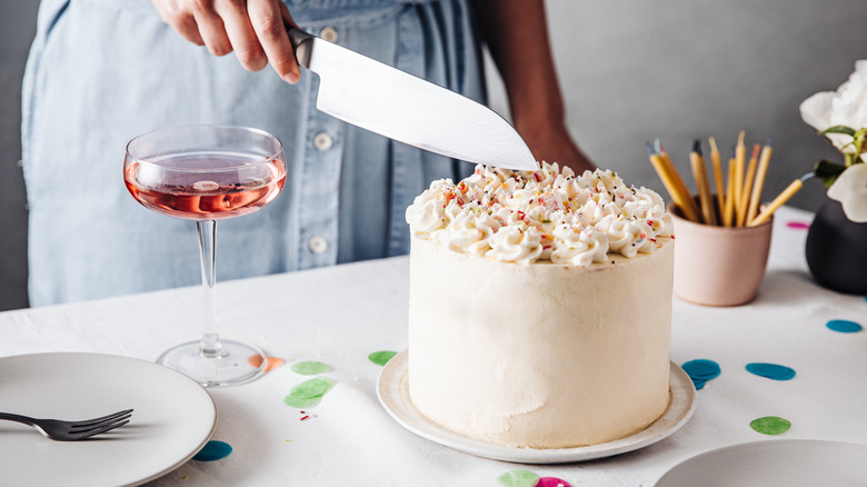 person with knife hovers over birthday cake